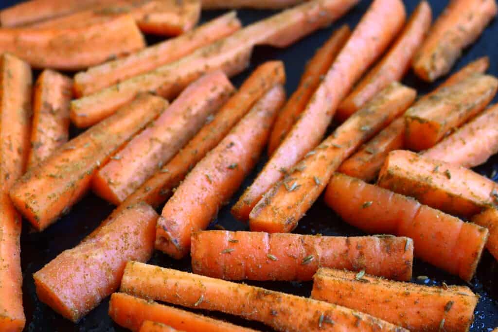Carrots coated in cumin on a roasting tin