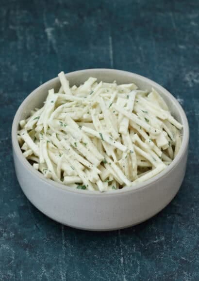 A close-up bowl of creamy Celeriac Remoulade garnished with fresh parsley
