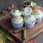 Spiced pumpkin muffins with a cream cheese topping on a board