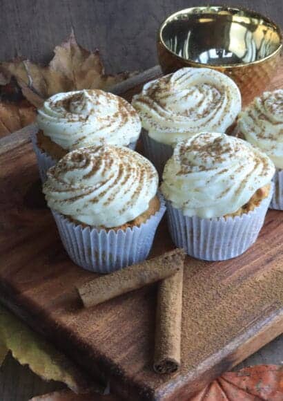 Spiced pumpkin muffins with a cream cheese topping on a board