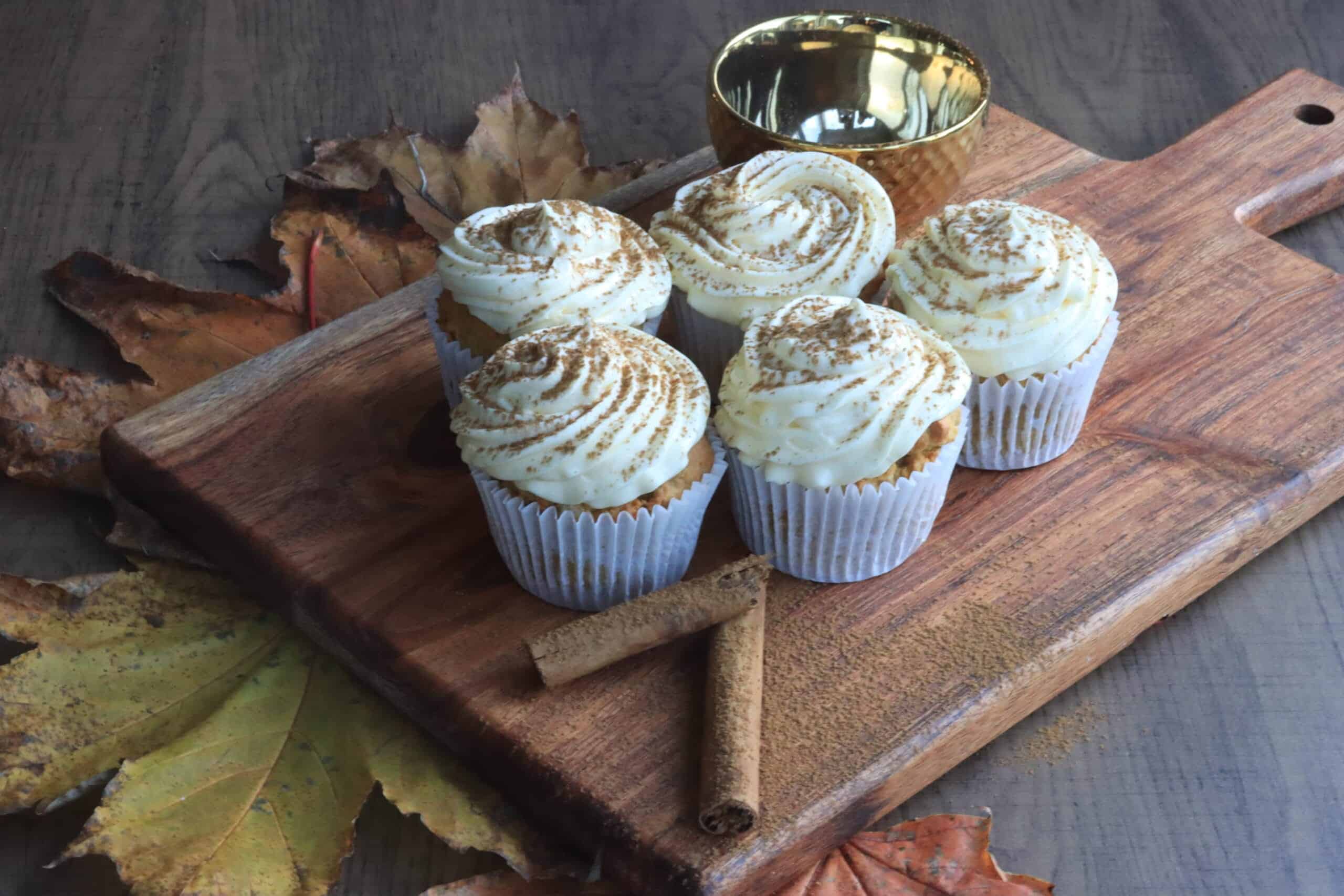 Spiced pumpkin muffins with a cream cheese topping on a board