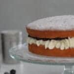 Victoria Sponge Cake with Mascarpone Cream Icing and Blackberry Jam on a glass cake stand
