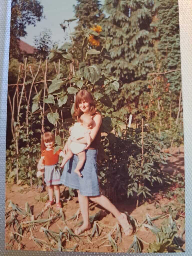 photo of Chloe with her Mum and baby sister in the middle of the vegetable patch