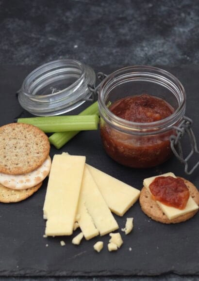 cheeseboard with crackers, cheddar, celery and a jar of apple chutney