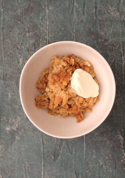 Apple crumble in a while bowl topped with creme fraiche