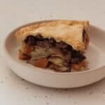 Plate with a slice of pasty pie showing the layers of vegetables, meat and finally the pastry on top