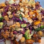 A rainbow bowl of vegetable, plant-protein, and nuts in a tahini dressing