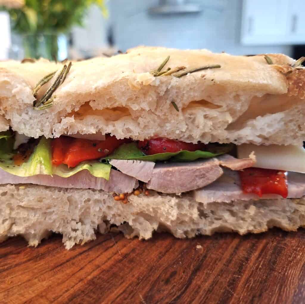 sliced focaccia bread filled with mustard, roast pork, roasted peppers, lettuce and cheese