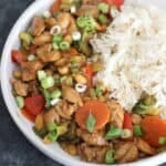 Kung Pao Chicken with extra vegetables and roasted peanuts served with steamed rice in a bowl