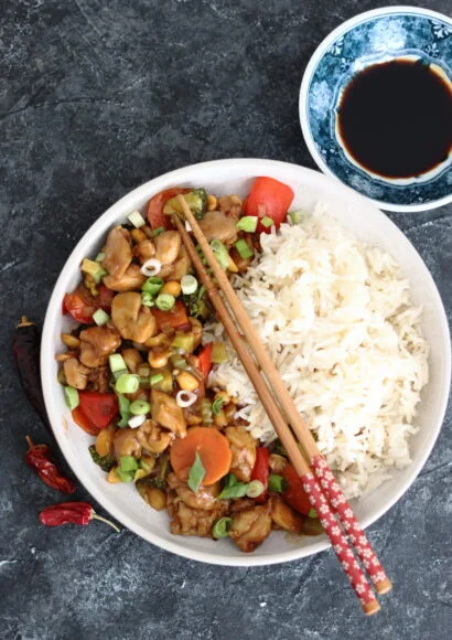 Kung Pao Chicken with extra vegetables and roasted peanuts served with steamed rice in a bowl