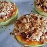 Stuffed Courgette Slice with Leftovers - A tray covered with foil with a large round of over-sized courgette, filled in the middle and topped with golden breadcrumbs and cheese