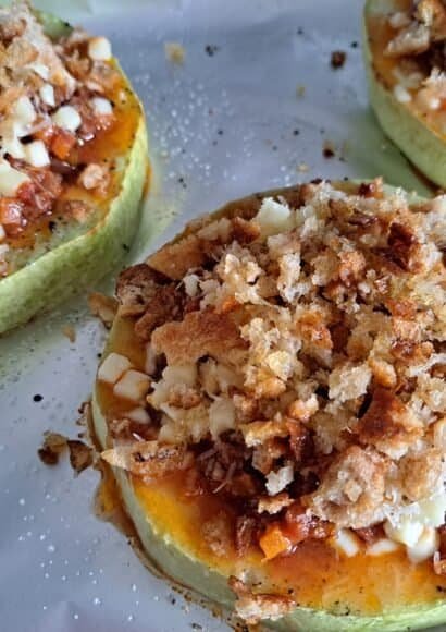 Stuffed Courgette Slice with Leftovers - A tray covered with foil with a large round of over-sized courgette, filled in the middle and topped with golden breadcrumbs and cheese