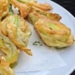 A plate of golden fried courgette flowers attached to baby courgettes.