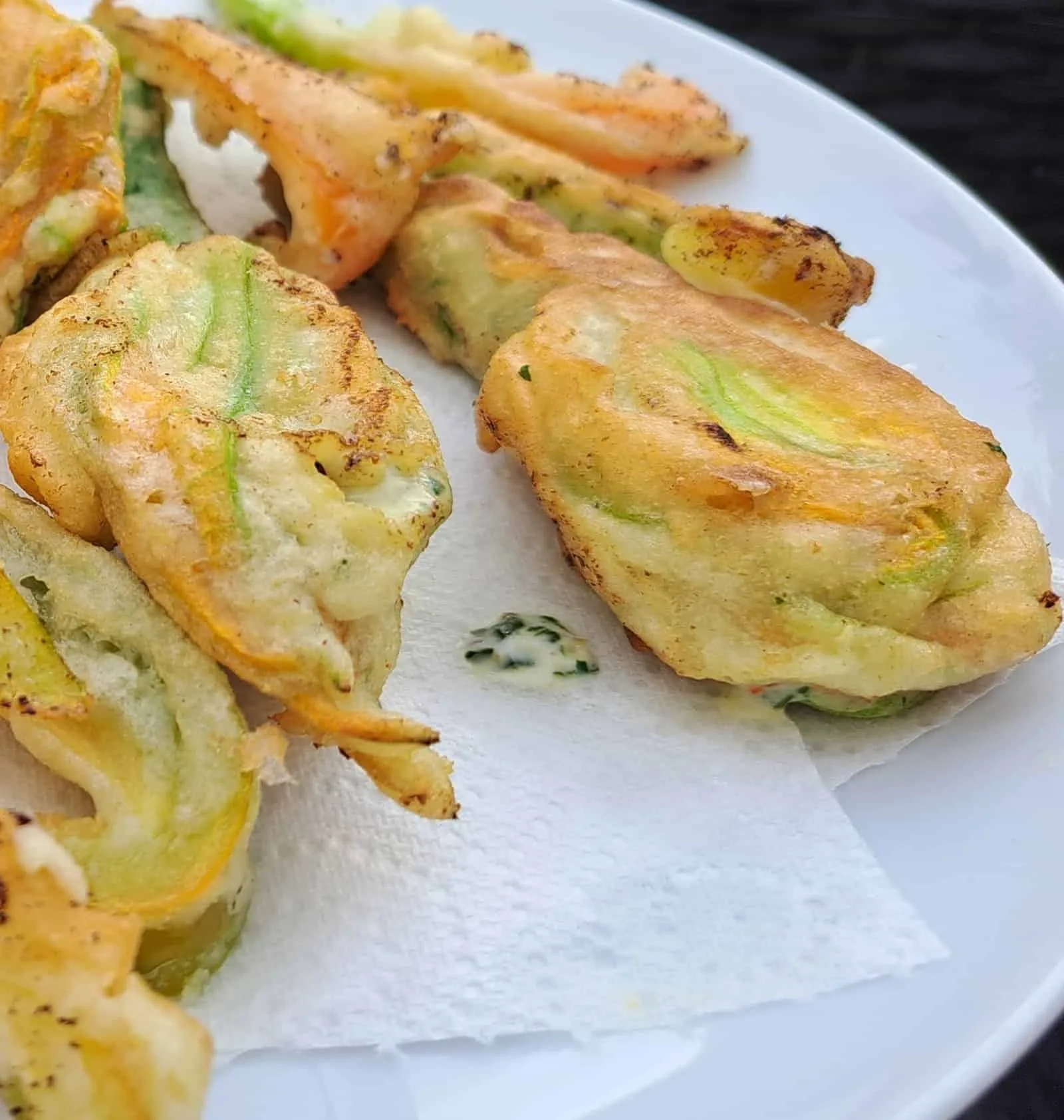 A plate of golden fried courgette flowers attached to baby courgettes.