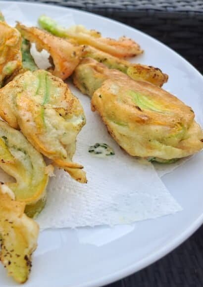 A plate of golden fried courgette flowers attached to baby courgettes.