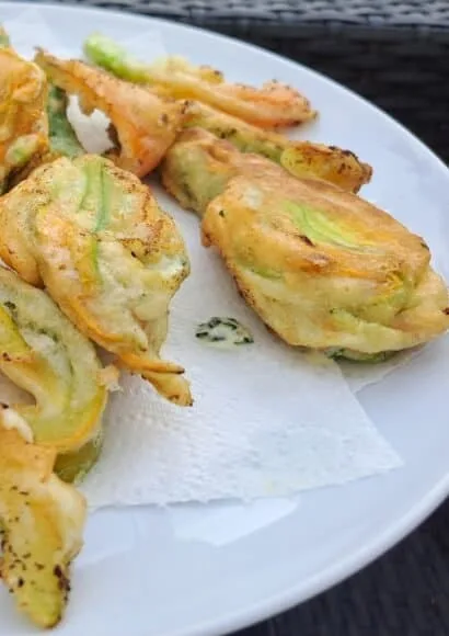 A plate of golden fried courgette flowers attached to baby courgettes.
