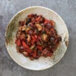 A speckled presentation bowl full of colourful ratatouille - including aubergine, courgette, peppers and tomatoes.
