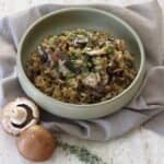 Bowl of creamy mushroom and leek risotto topped with parsley.