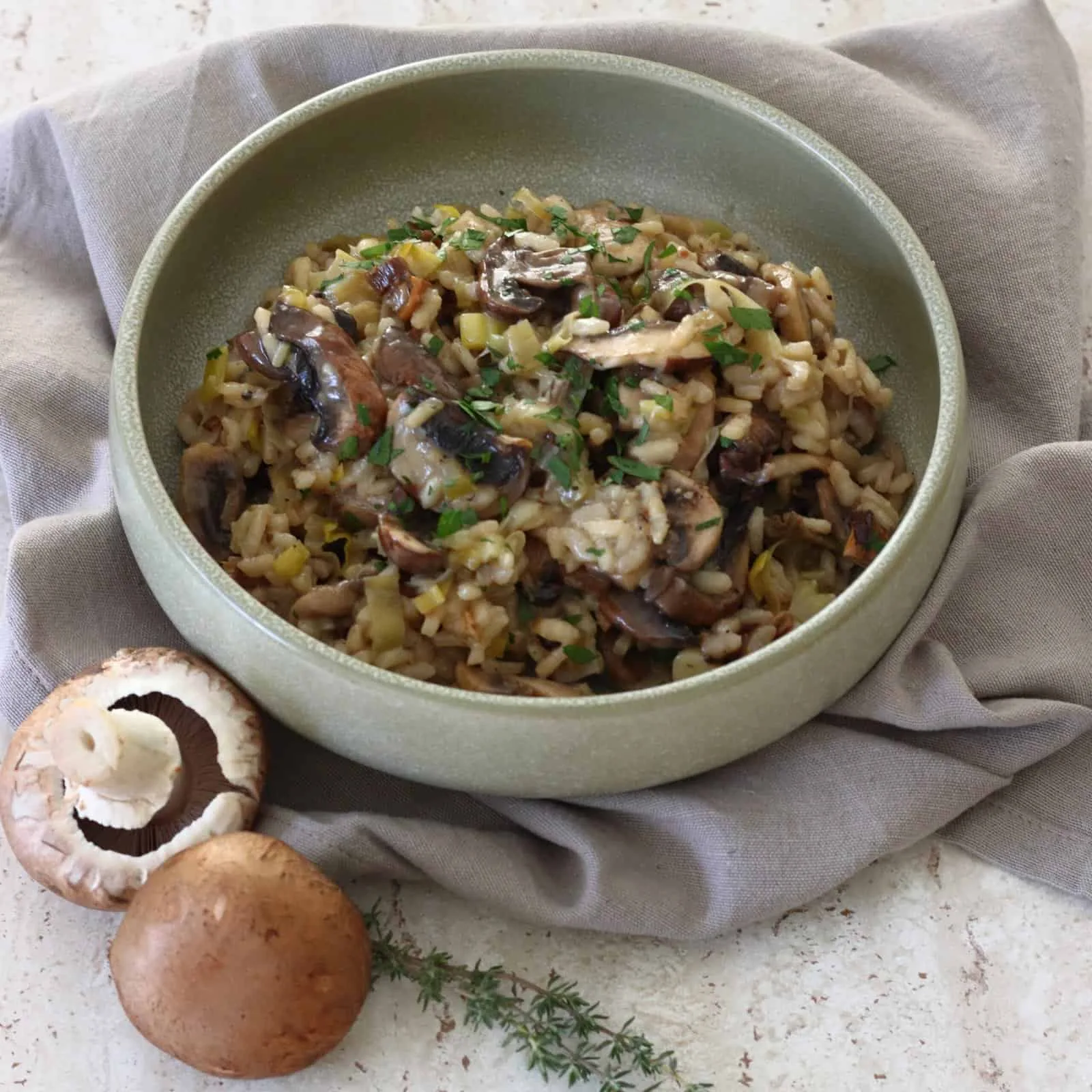Bowl of creamy mushroom and leek risotto topped with parsley.